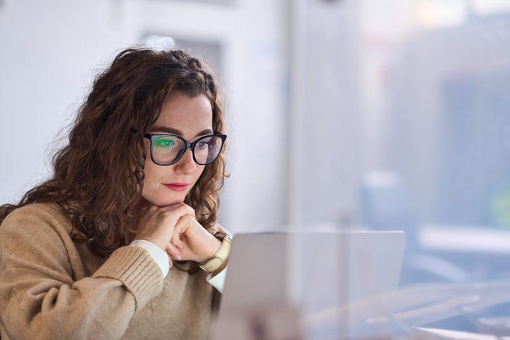 1455362922 Young serious busy professional business woman employee or student wearing glasses using laptop watching online webinar or training web course, looking at computer, thinking, doing research.