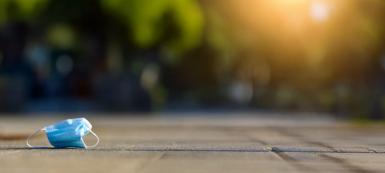 A disposable mask lies on the ground.